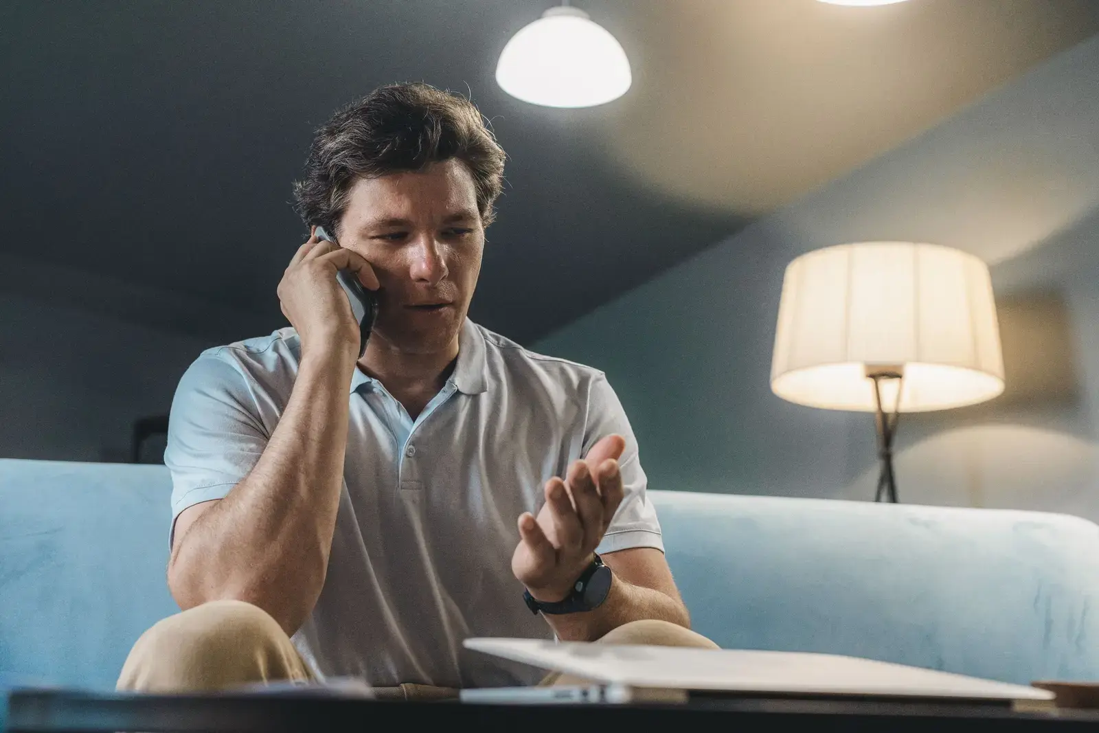 Man at home in the evening, calling for help on his phone