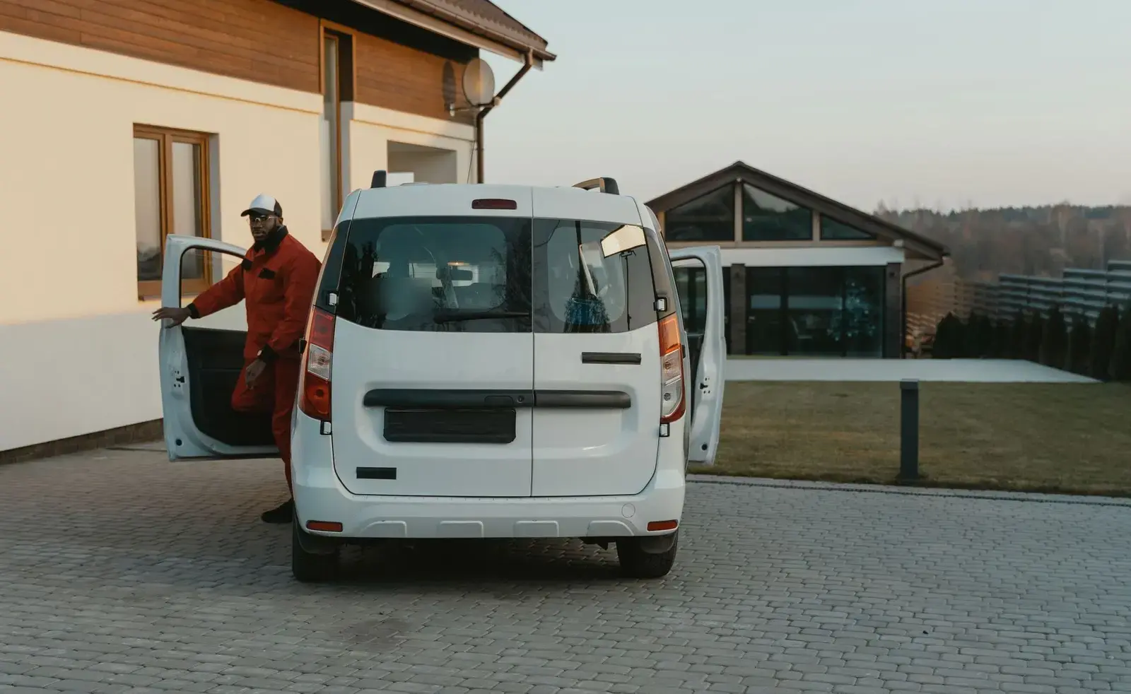 Technician stepping out of a white service van parked in a home driveway